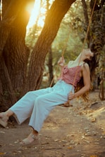 Woman exercising joyfully in a sunny park surrounded by trees.