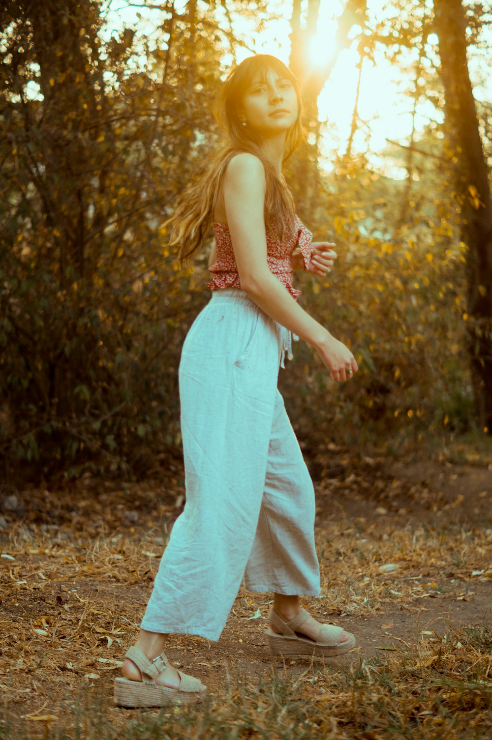 woman in white spaghetti strap dress standing on brown soil during daytime