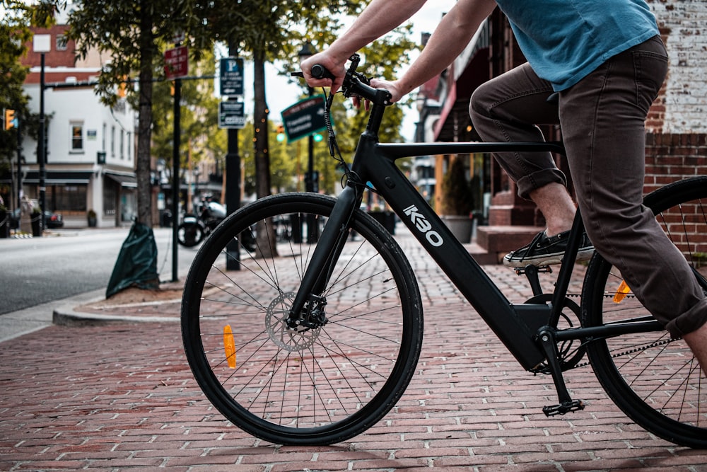 man in black jacket and gray pants standing beside black bicycle near body  of water during photo – Free Bicycle Image on Unsplash