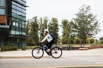 man in white shirt riding bicycle on road during daytime