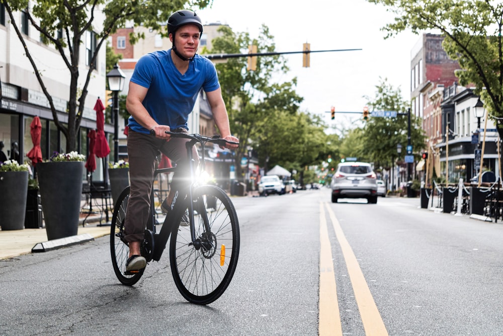 man in blue shirt riding a black electric bicycle