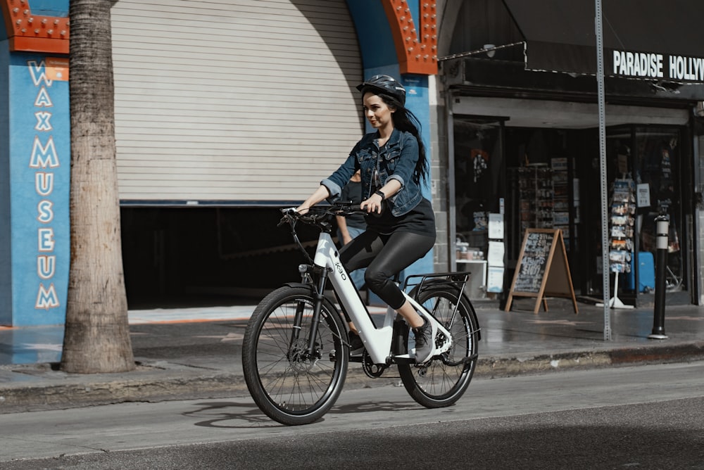 昼間、黒い自転車に乗る青いデニムジャケットの女性