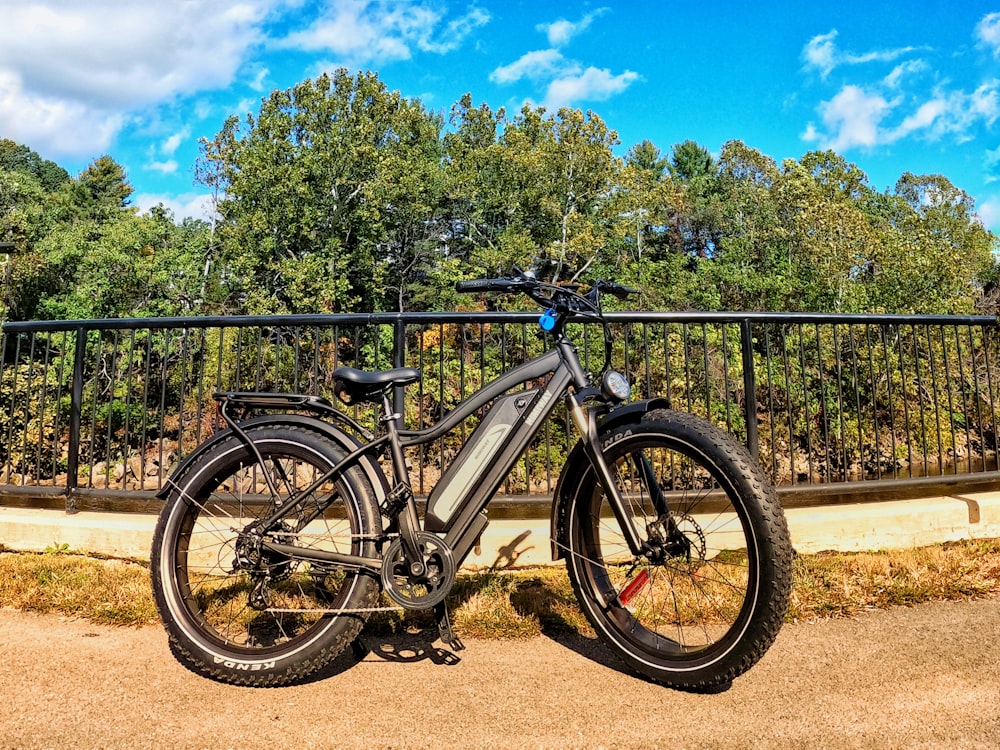 black and white mountain bike parked beside black metal fence during daytime