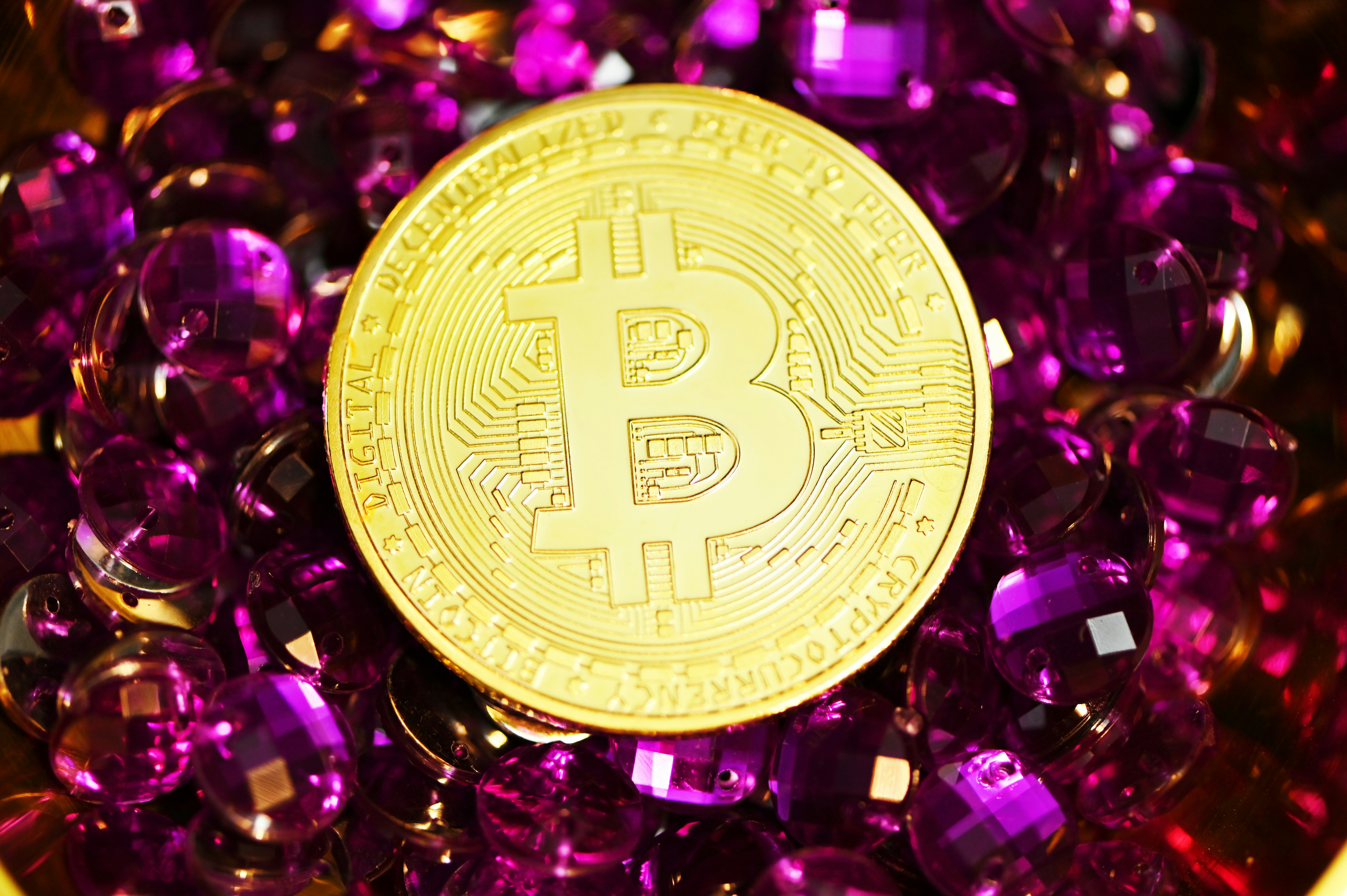 A Bitcoin surrounded by purple gems.