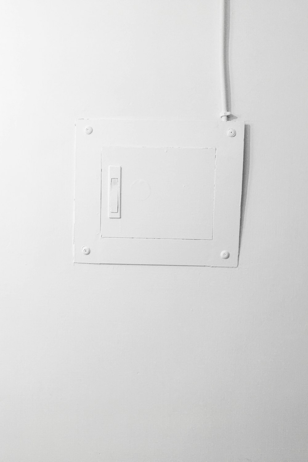 weißer elektrischer Schalter an weiß gestrichener Wand montiert