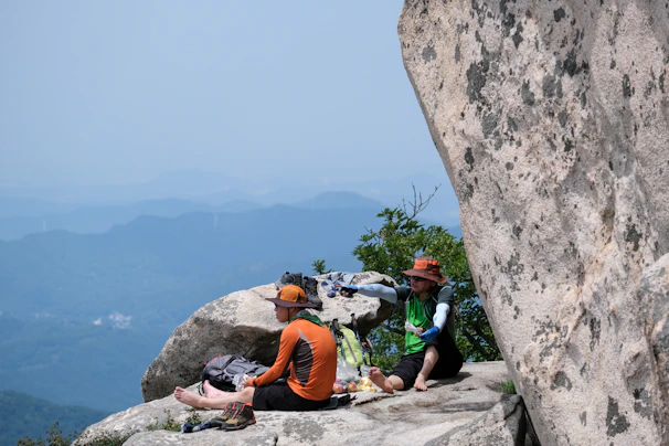 A couple enjoying a private picnic on a lush green mountain plateau under a clear blue sky.