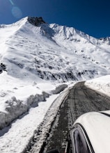 black car on road near snow covered mountain during daytime