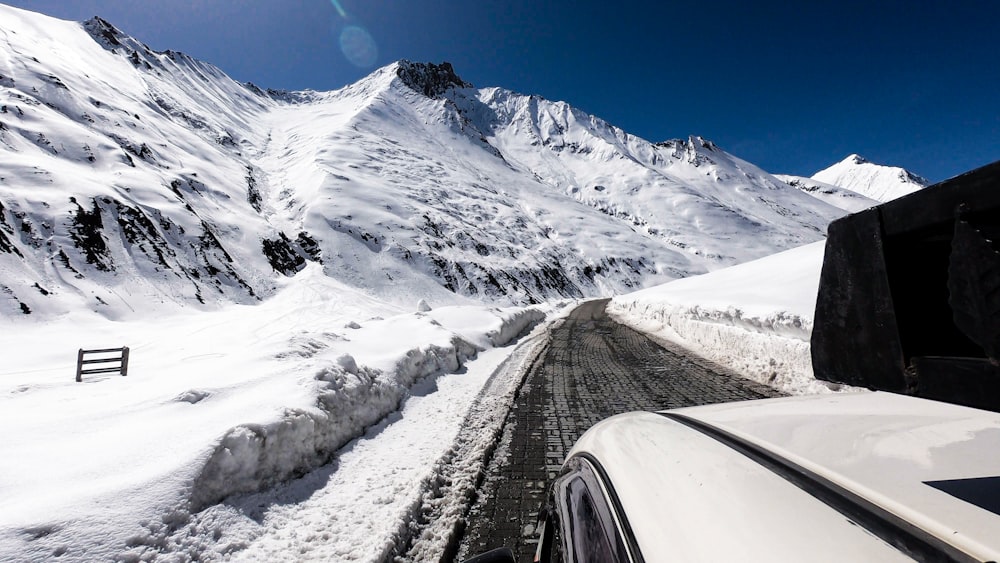 Coche negro en la carretera cerca de la montaña cubierta de nieve durante el día