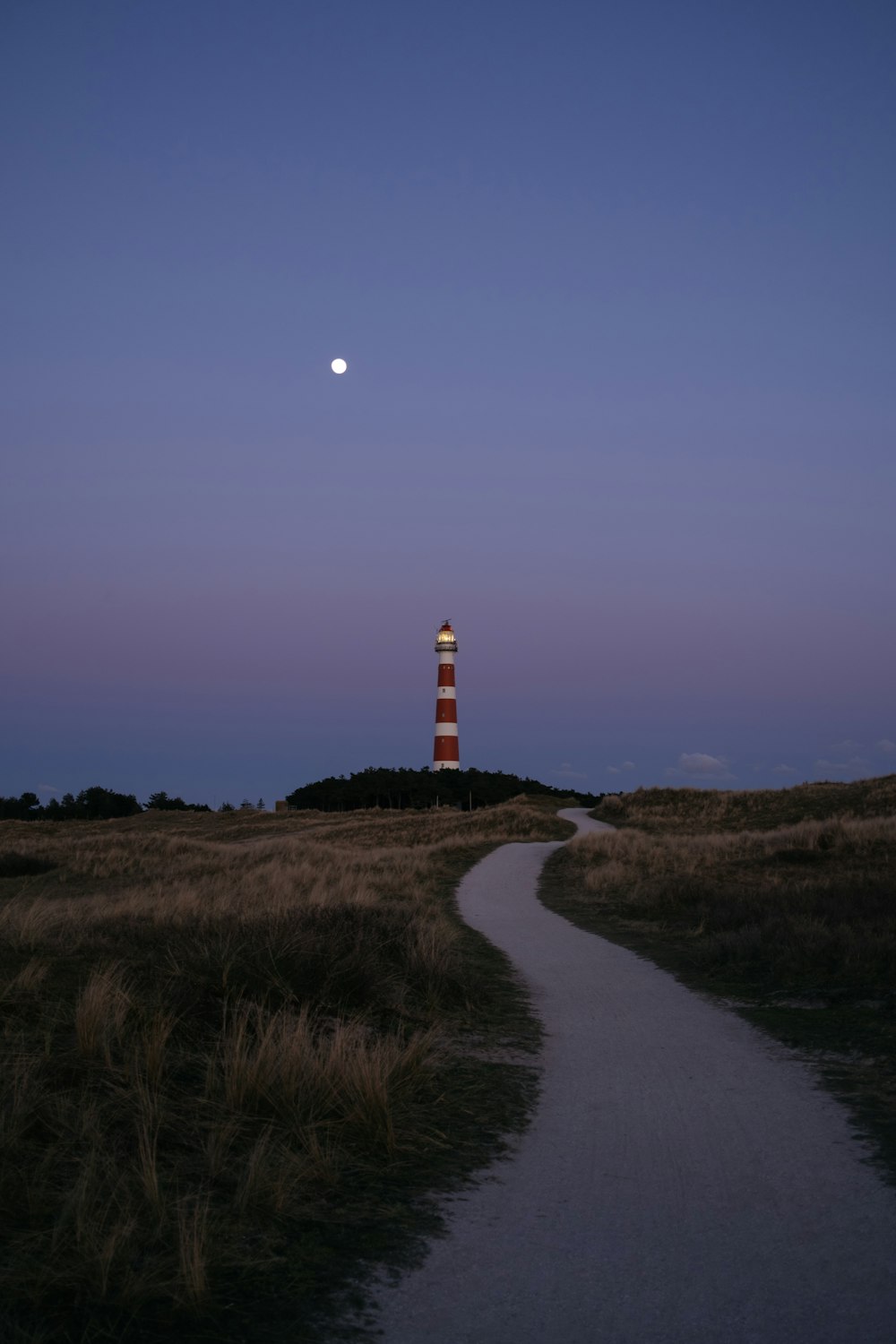 Faro bianco e rosso vicino al campo di erba verde durante il giorno