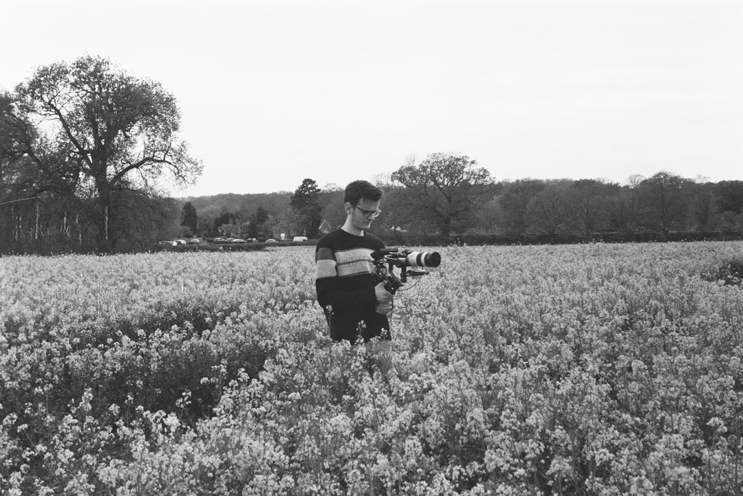 grayscale photo of man and woman kissing on flower field