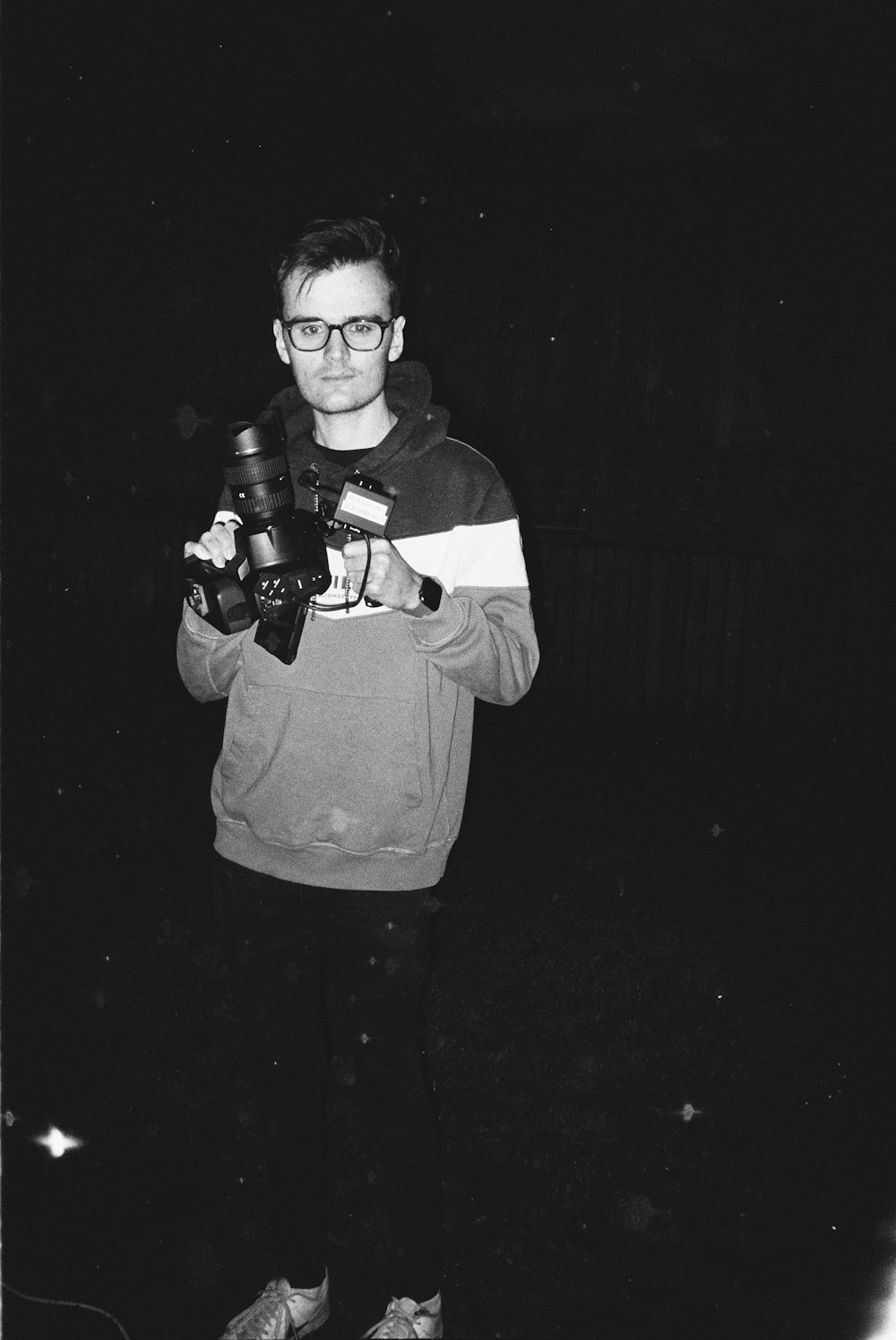 man in black and white hoodie holding dslr camera