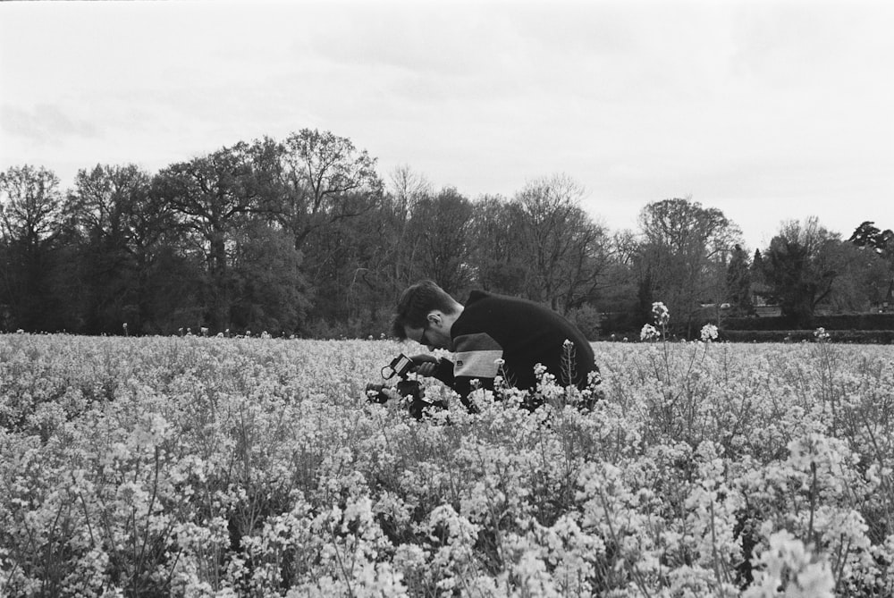 grayscale photo of man and woman sitting on grass field