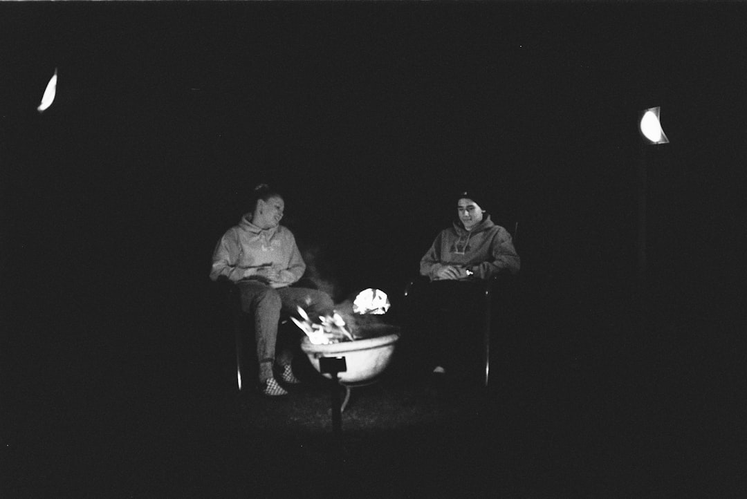 man and woman sitting on chair in front of fire pit
