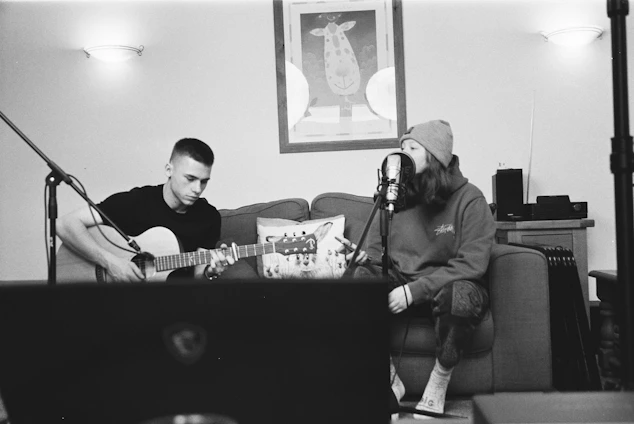 A candid photo of a female singer-songwriter playing guitar in a cozy studio filled with warm light.