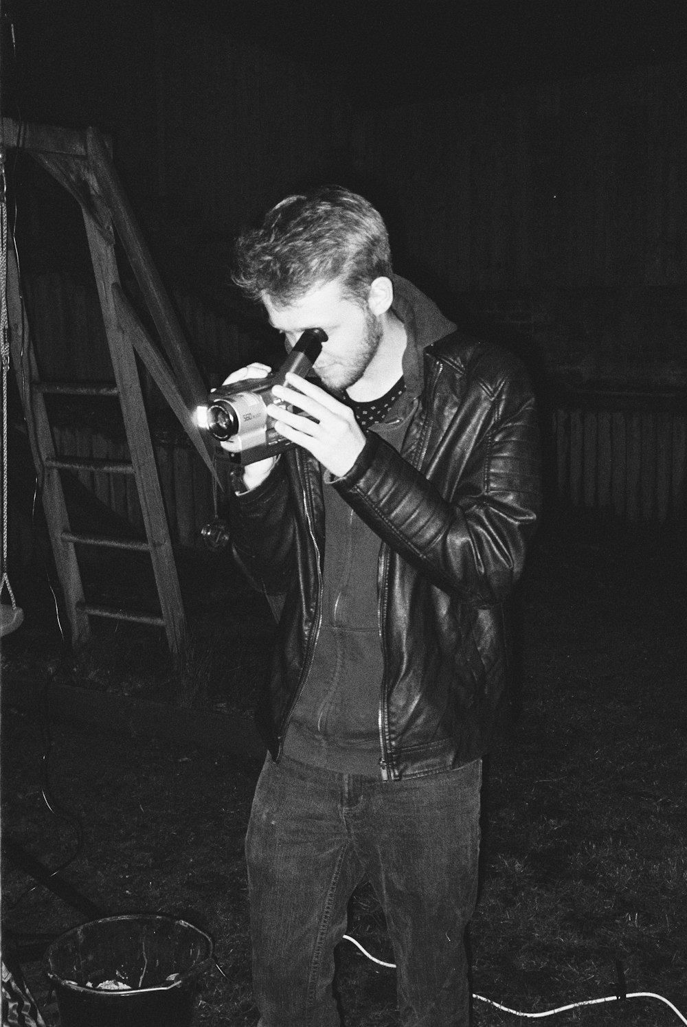 man in black leather jacket holding black dslr camera