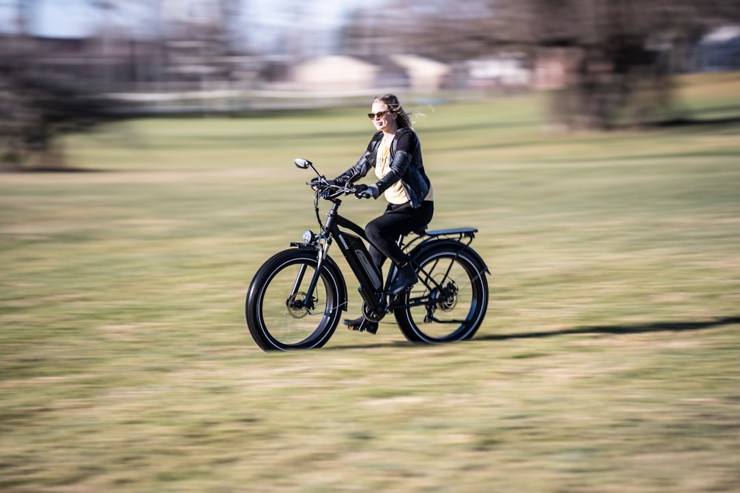 woman in black jacket riding on black motorcycle on green grass field during daytime