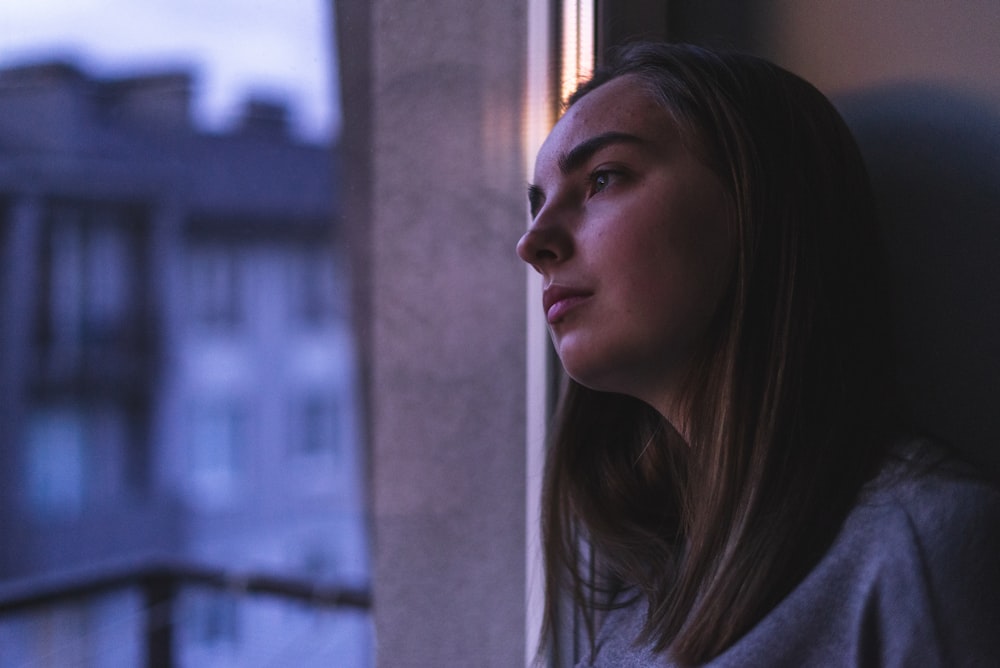 woman in white shirt looking at the window during daytime