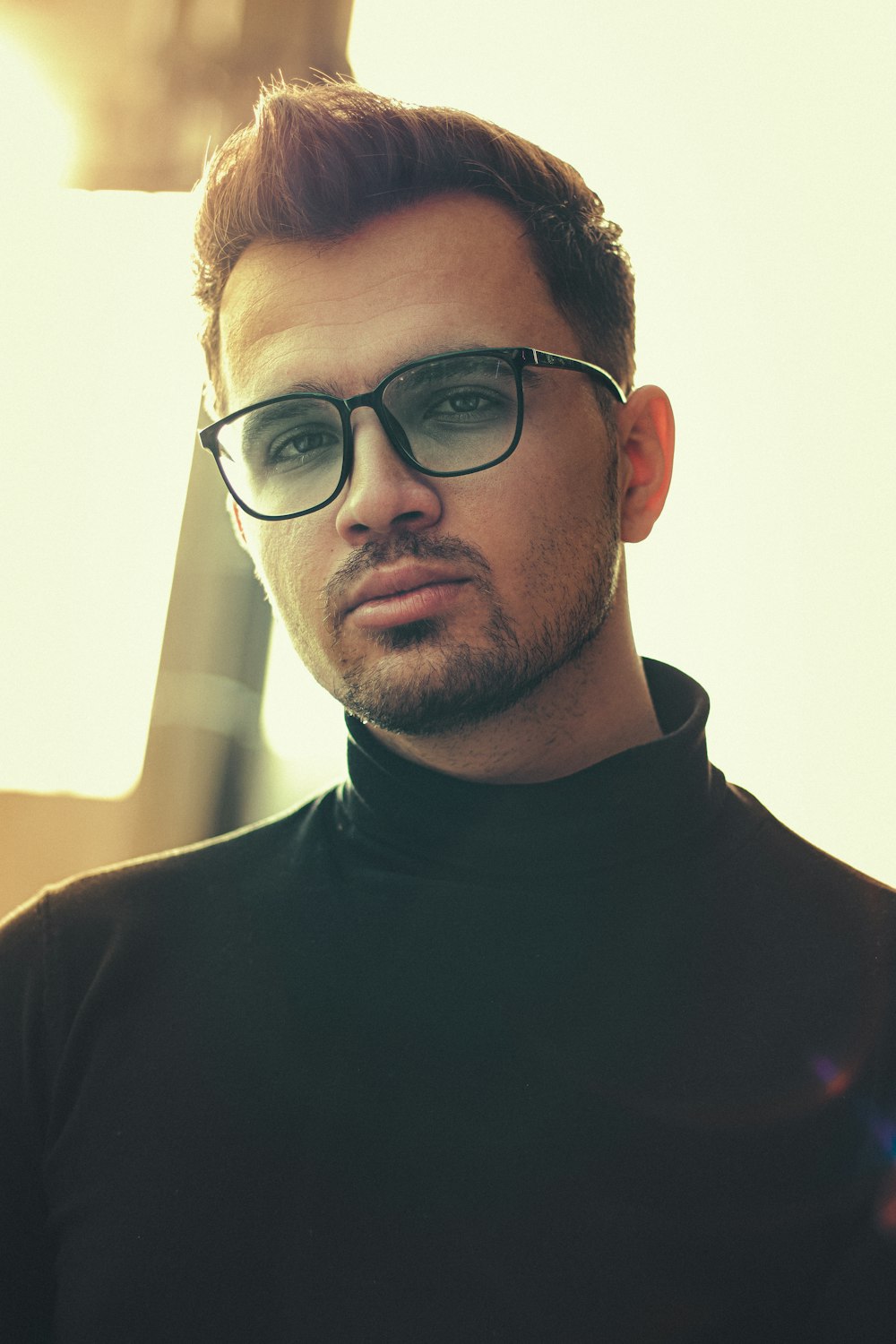 Homme en chemise noire à col rond portant des lunettes à monture noire