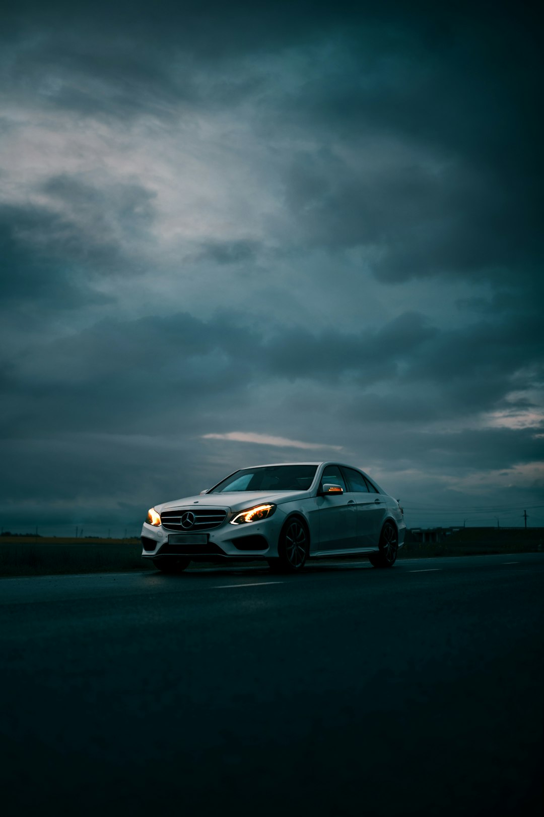 white sedan on road under gray clouds