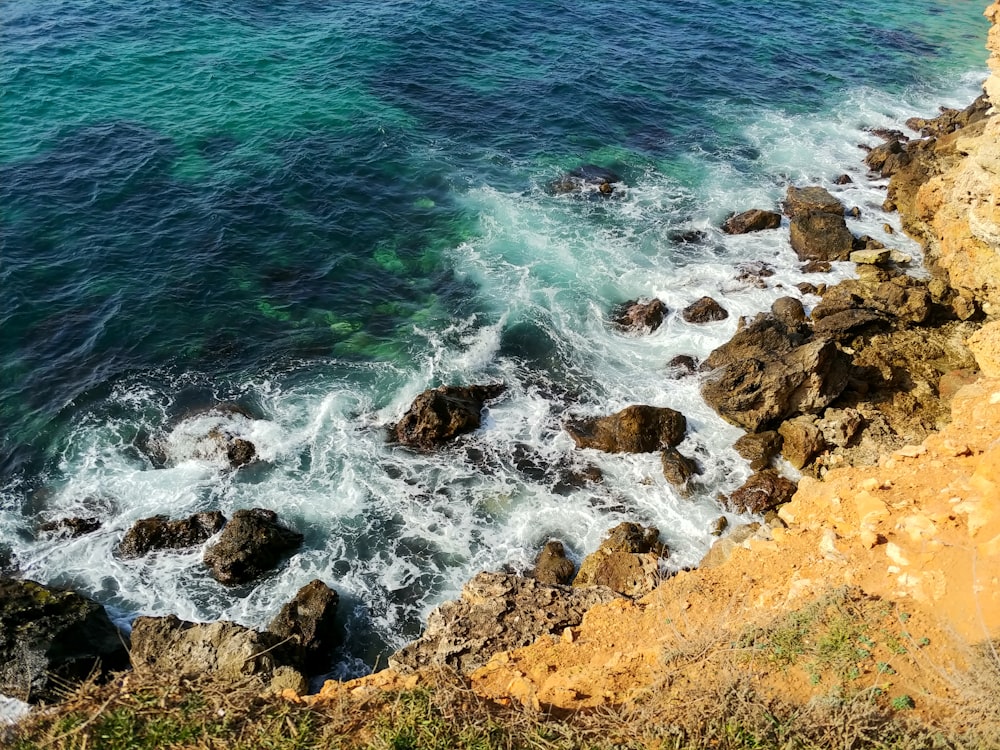 braunes Felsufer mit blauem Meerwasser tagsüber