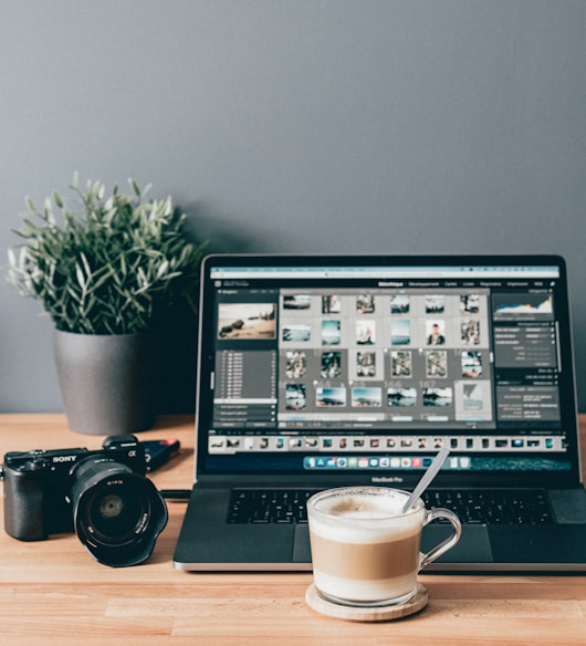 black laptop computer beside white ceramic mug on brown wooden table