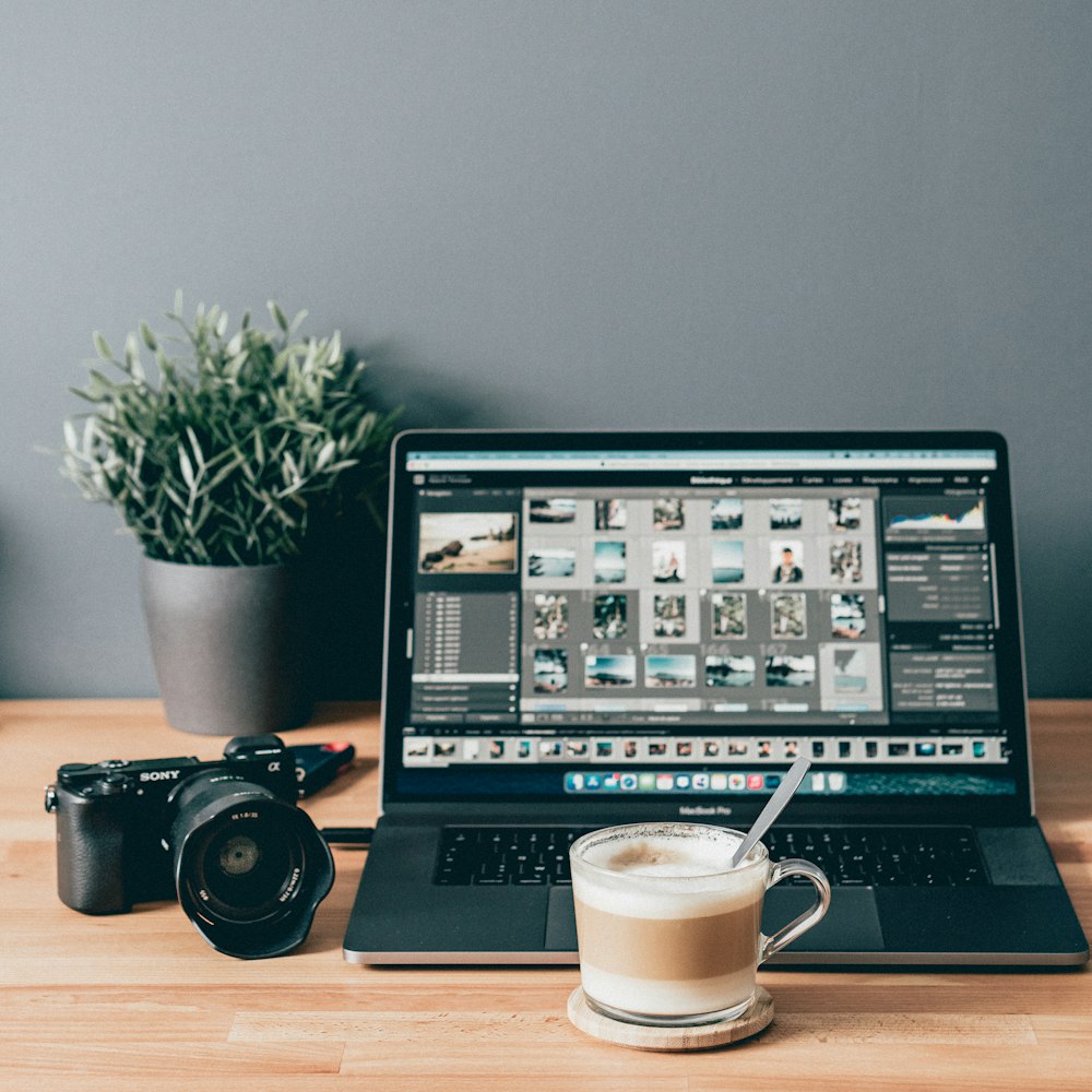 black laptop computer beside white ceramic mug on brown wooden table