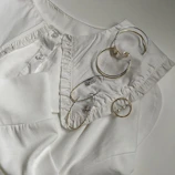 Flat lay of trendy rings and earrings arranged on a soft beige fabric background.