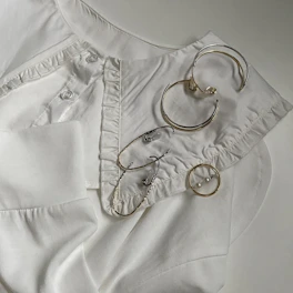 Array of jump rings and earring backs in brass and silver, arranged neatly on a textured surface.