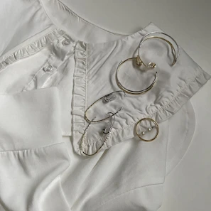 Flat lay of trendy rings and earrings arranged on a soft beige fabric background.