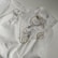 An arrangement of several pieces of metal jewelry, including hoop earrings and a ring, laid out on a white collared shirt with button and ruffle details.