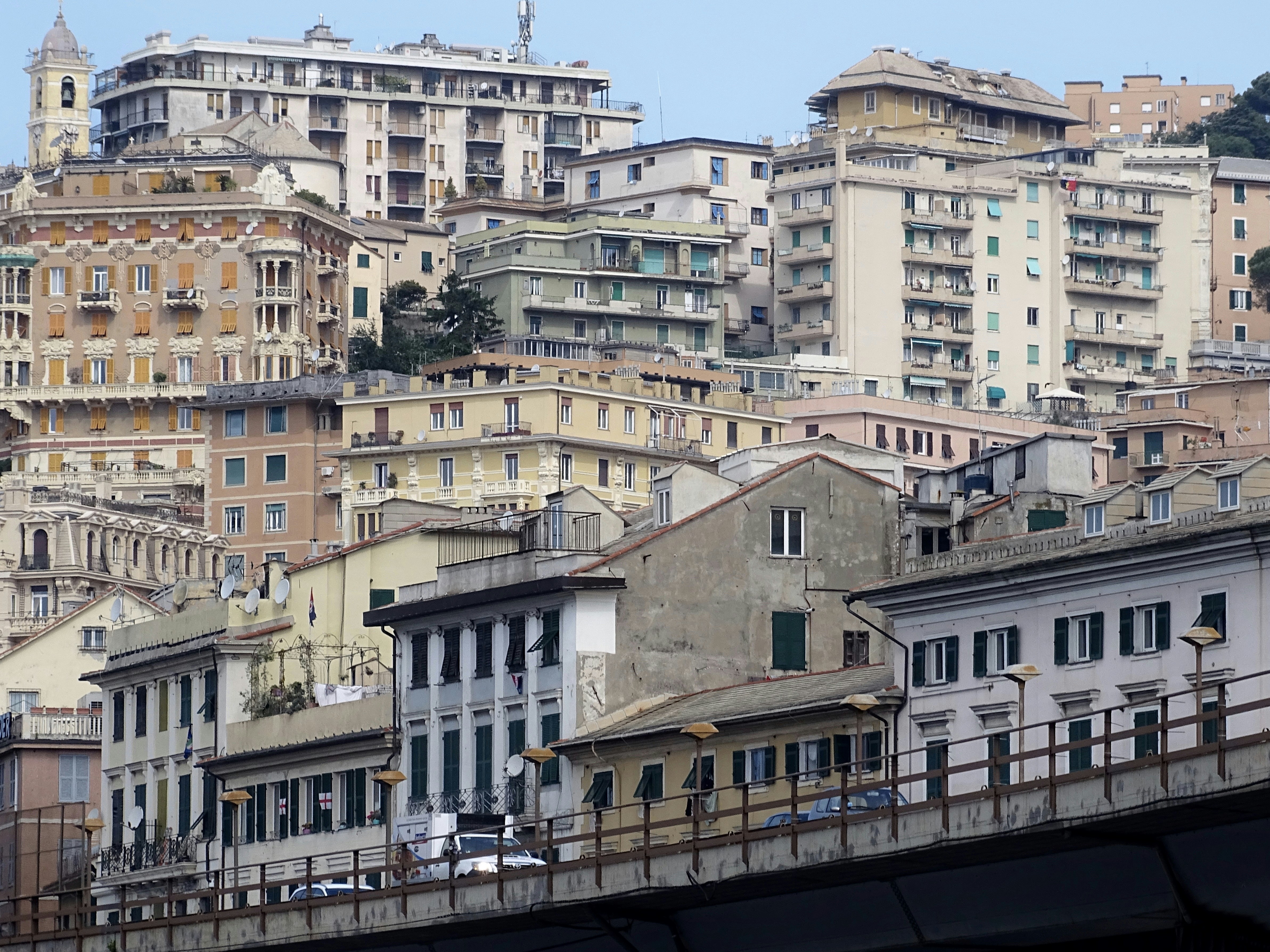 white and brown concrete building near body of water during daytime, The lovely city of Genoa Italy. Just walking through the streets and looking up at the buildings above the flyover.  
