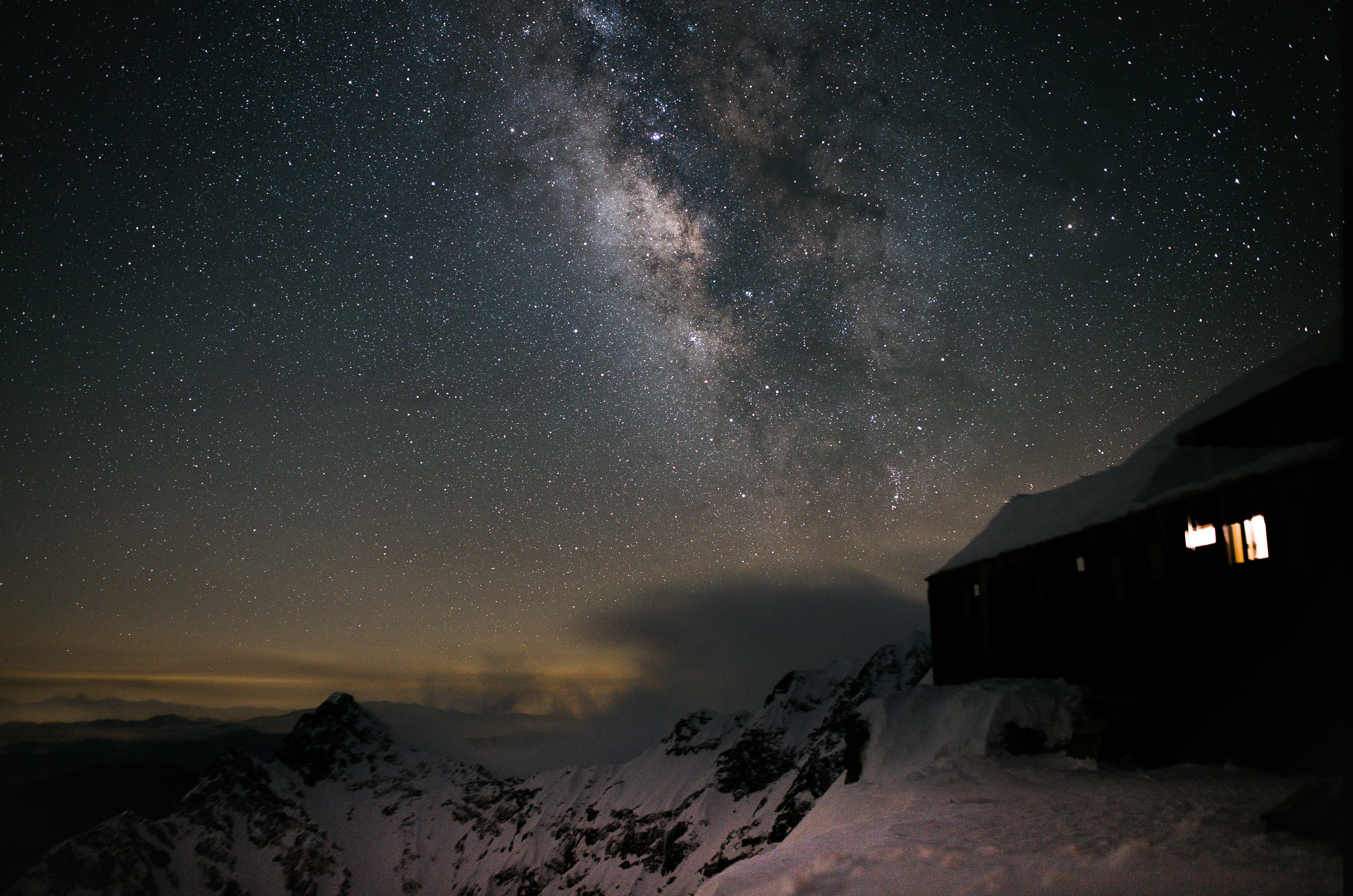 雪の上に立つ家と星空