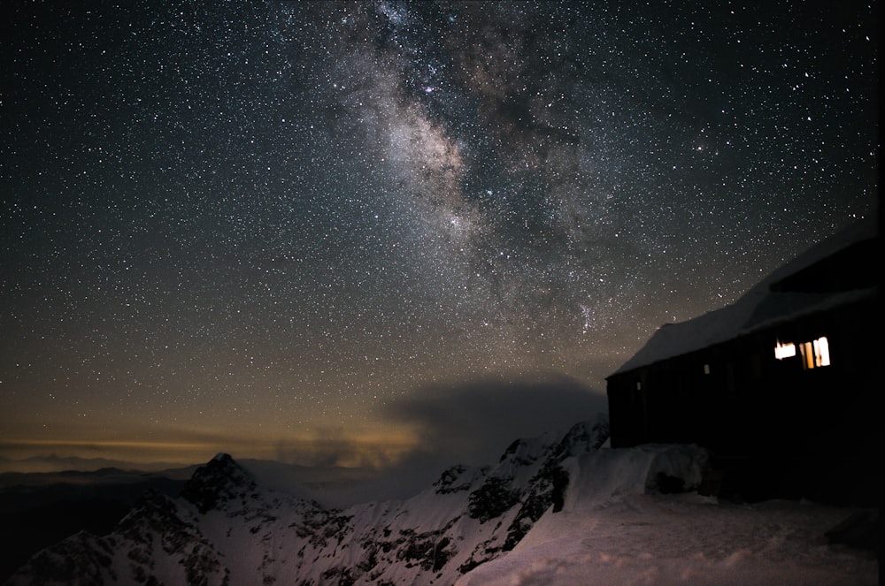 Braunes Holzhaus auf schneebedecktem Boden unter sternenklarer Nacht