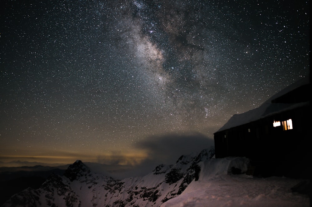 Casa de madera marrón en suelo cubierto de nieve bajo la noche estrellada
