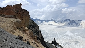brown rocky mountain under white clouds during daytime