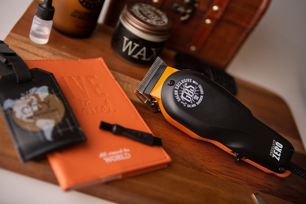 orange book beside black and white round container on brown wooden table