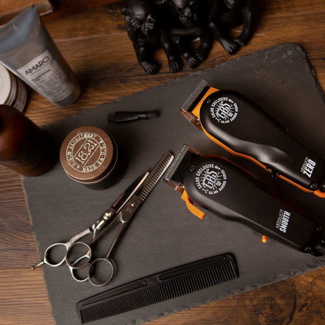 Two hair clippers, scissors, a comb and grooming products on a slate board
