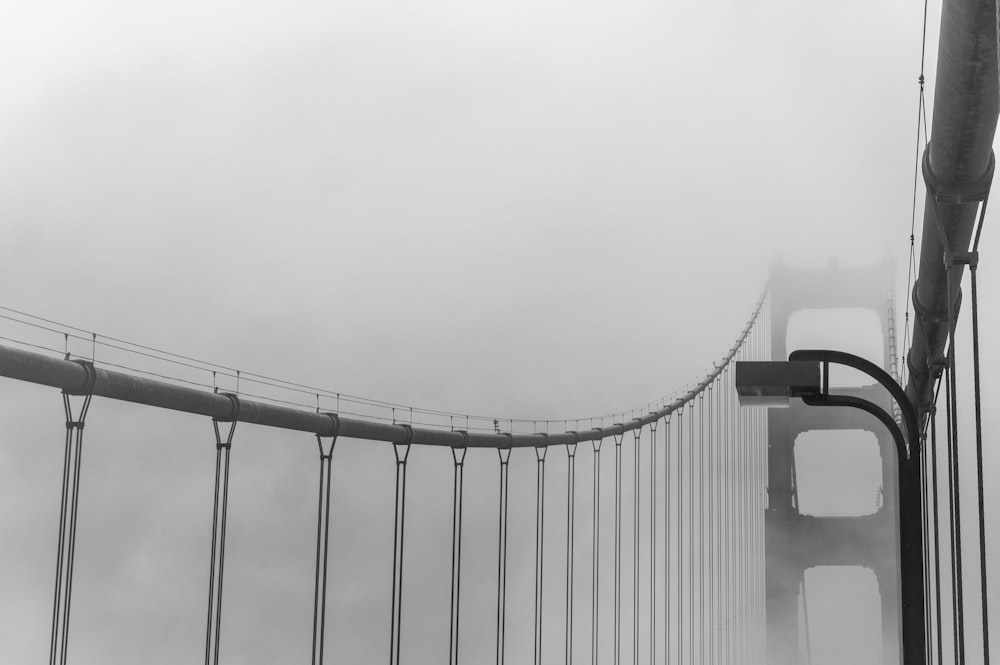 grayscale photo of bridge covered with fog