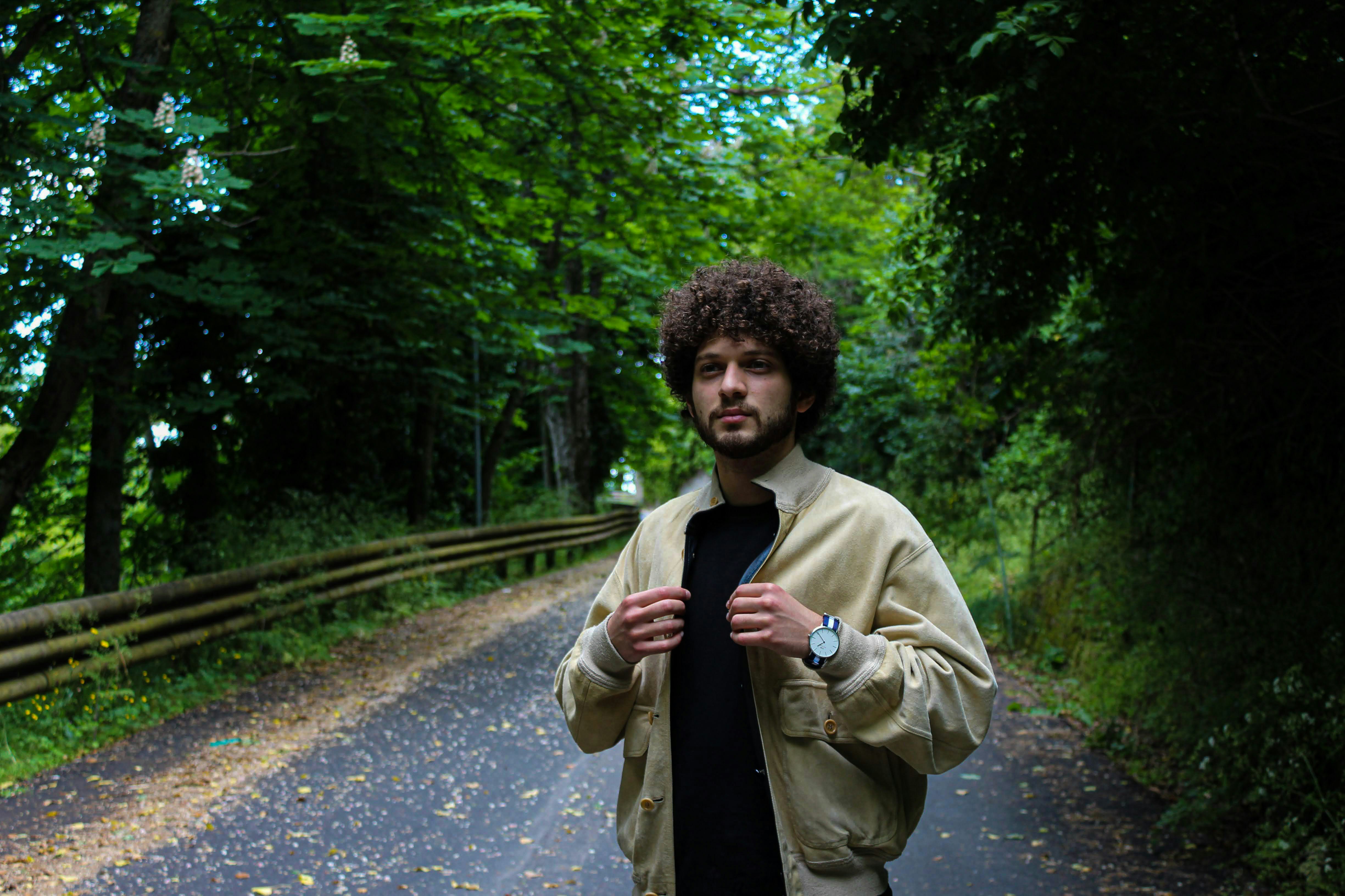 man in brown coat standing on road during daytime