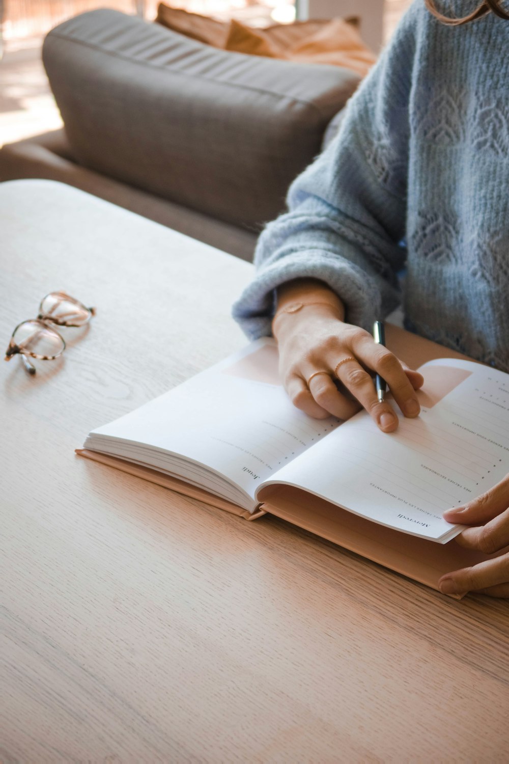 person in gray sweater holding white book