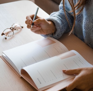 woman in white long sleeve shirt holding pen writing on white paper