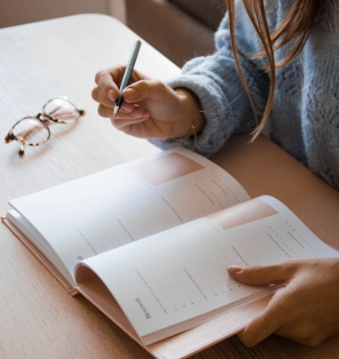 woman in white long sleeve shirt holding pen writing on white paper