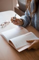woman in white long sleeve shirt holding pen writing on white paper
