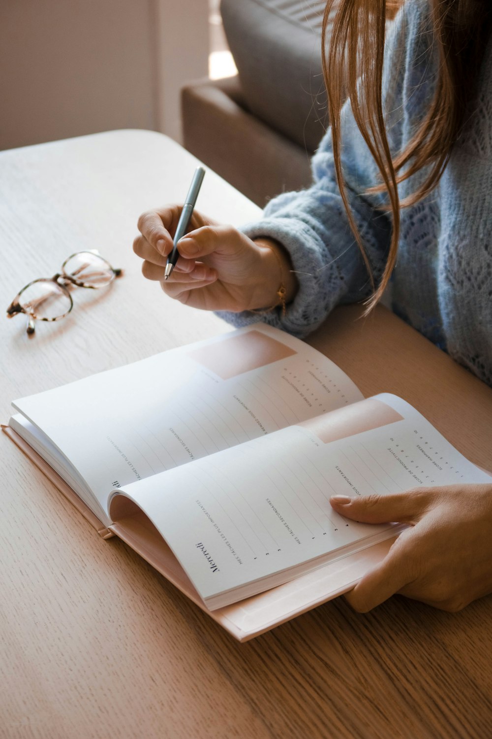 woman in white long sleeve shirt holding pen writing on white paper