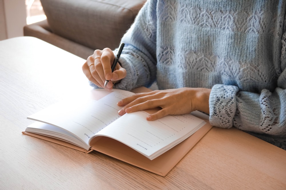 woman in white and gray sweater writing on white paper