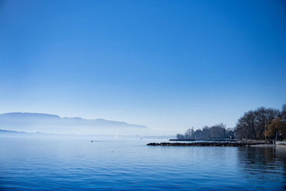 Serene lake surrounded by mountains and trees with calm water reflecting landscape perfectly