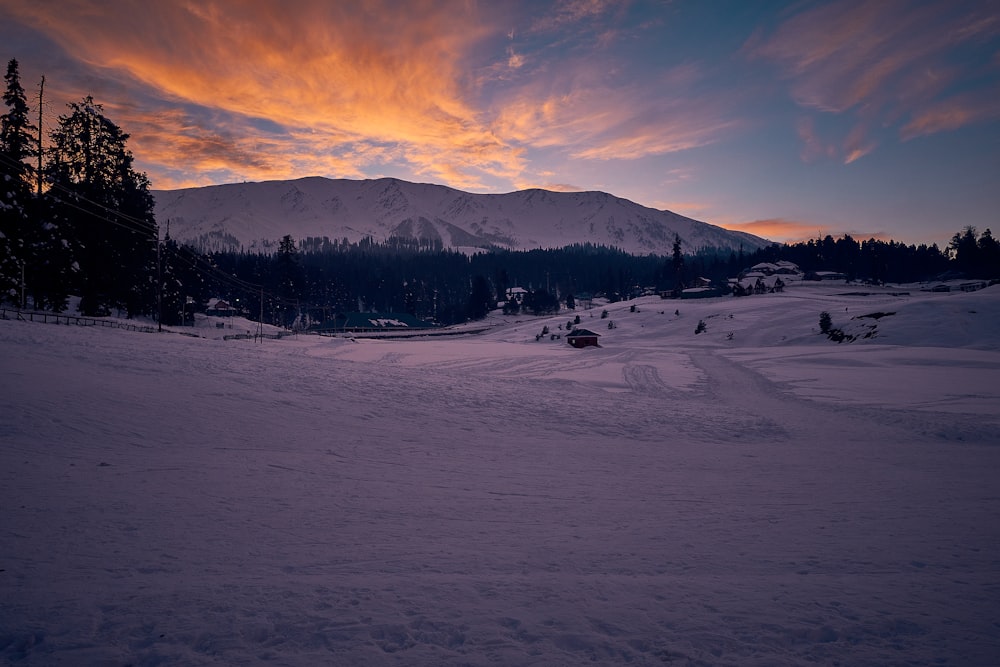 snow covered field near mountain under cloudy sky during daytime