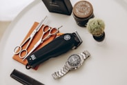 silver link bracelet round analog watch beside black leather pouch and silver and gold link bracelet