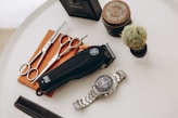 silver link bracelet round analog watch beside black leather pouch and silver and gold link bracelet