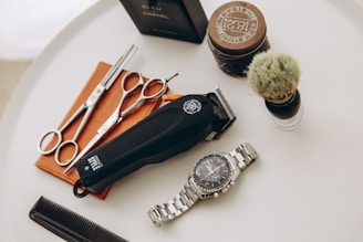 silver link bracelet round analog watch beside black leather pouch and silver and gold link bracelet